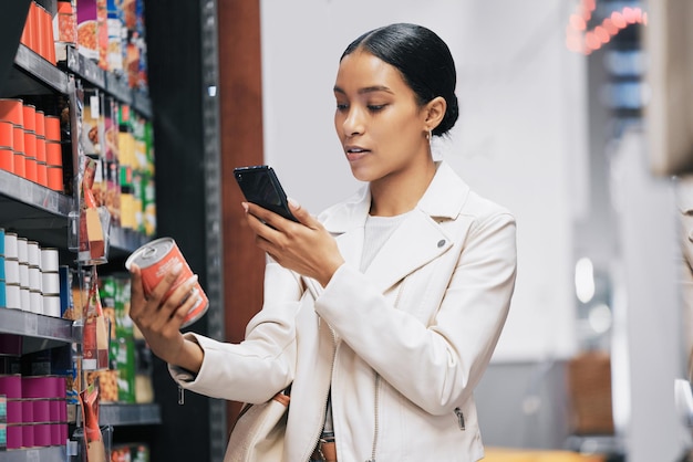 Client de supermarché et vérification des prix sur smartphone pour comparer le coût du produit sur l'application de commerce électronique Inflation de l'épicerie et augmentation des dépenses avec les consommables essentiels au style de vie