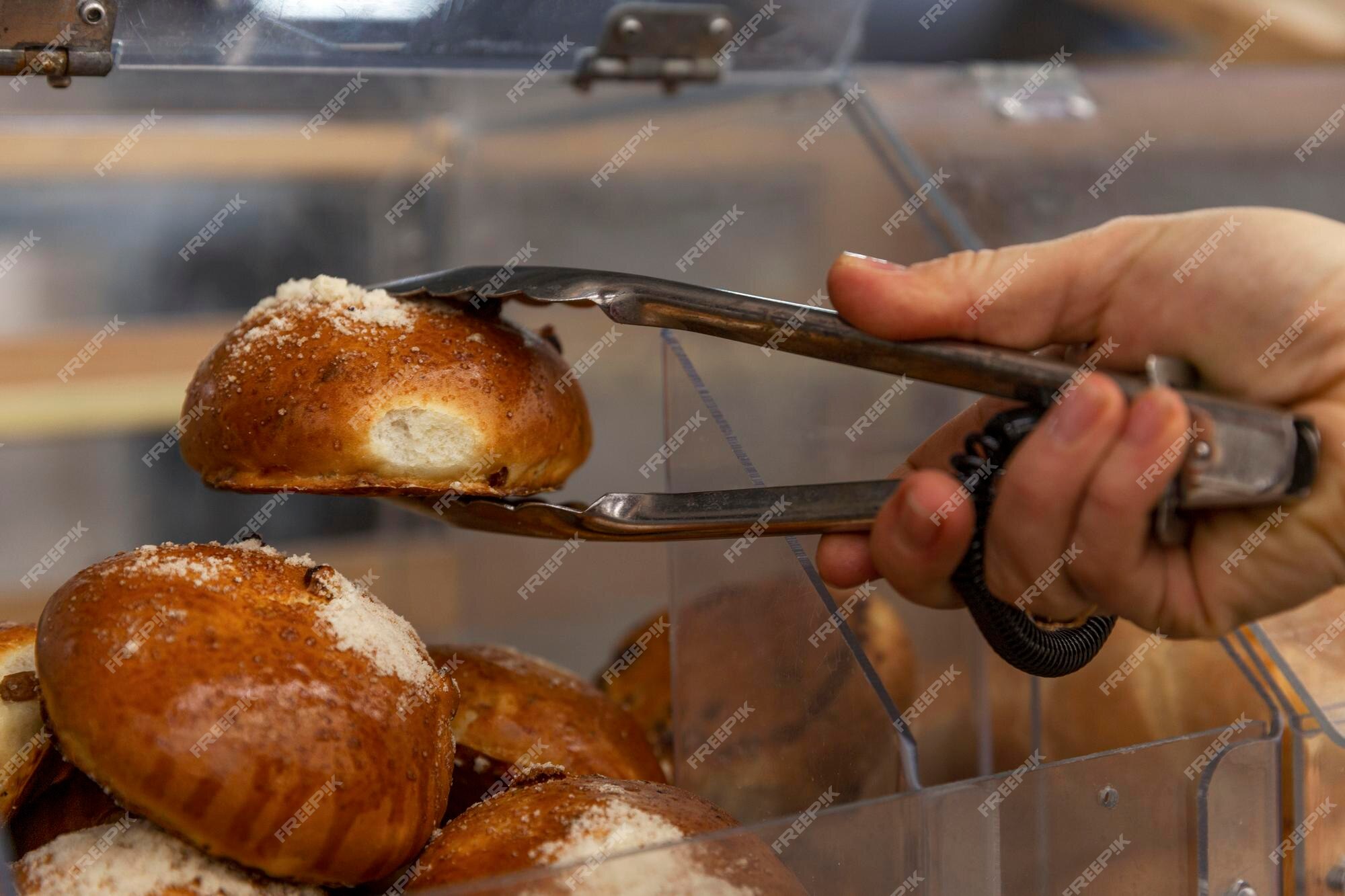 Le Client Tient Un Petit Pain Frais Sucré Avec Des Pinces Métalliques Dans  Le Magasin Gros Plan