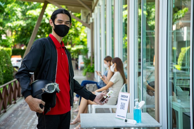 Client utilisant un téléphone portable pour s'enregistrer avant d'entrer dans le restaurant. Empêcher, vérifier et nettoyer avant de commander de la nourriture. Nettoyer avec de l'alcool