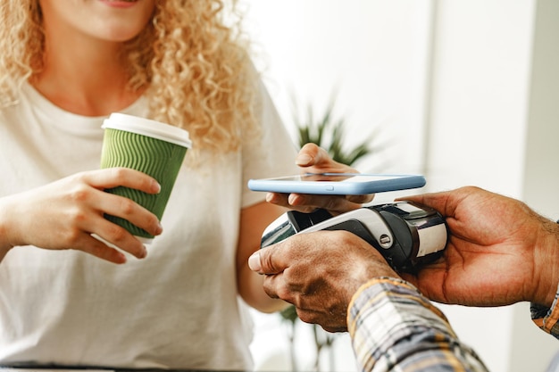 Cliente d'un café payant un café par téléphone portable à l'aide de la technologie sans contact