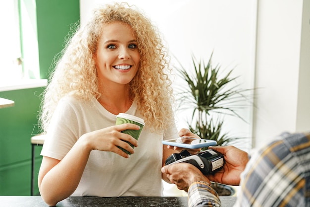 Cliente d'un café payant un café par téléphone portable à l'aide de la technologie sans contact