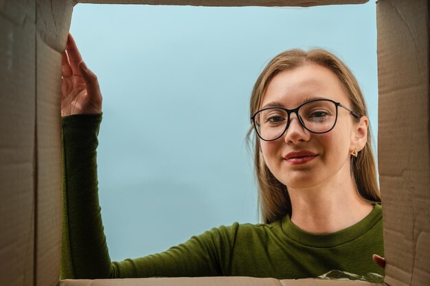 Photo une cliente heureuse ouvre une boîte en carton et regarde à l'intérieur.