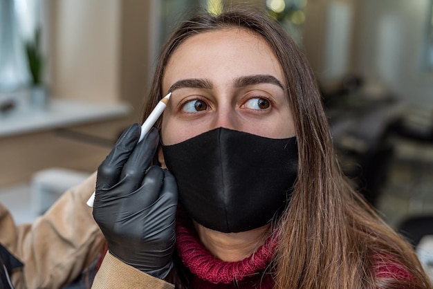 Une cliente d'un maître de salon à succès modélise la forme des sourcils pendant une pandémie