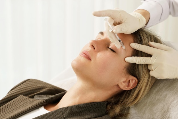 Cliente pendant les injections de remplissage facial dans une clinique médicale esthétique