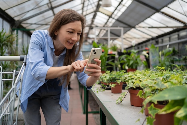 Une cliente prend une photo d'une plante en pot avec son smartphone alors qu'elle fait ses courses dans un magasin d'amélioration de l'habitat.