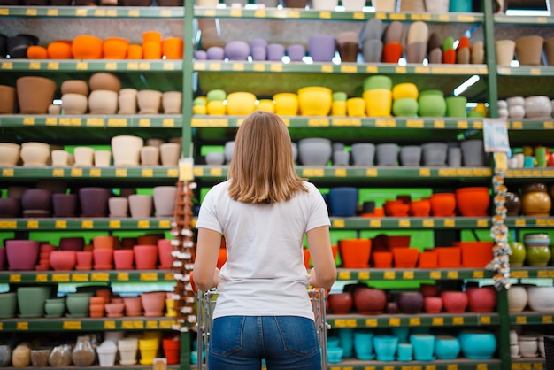 Clientèle Féminine à L'étagère Avec Des Pots De Fleurs, Vue Arrière, Boutique Pour Le Jardinage. Femme D'acheter Du Matériel En Magasin Pour La Floriculture, L'achat D'instruments De Fleuriste