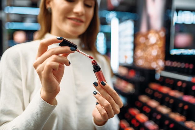 Clientèle féminine regarde le crayon à lèvres dans un magasin de cosmétiques.