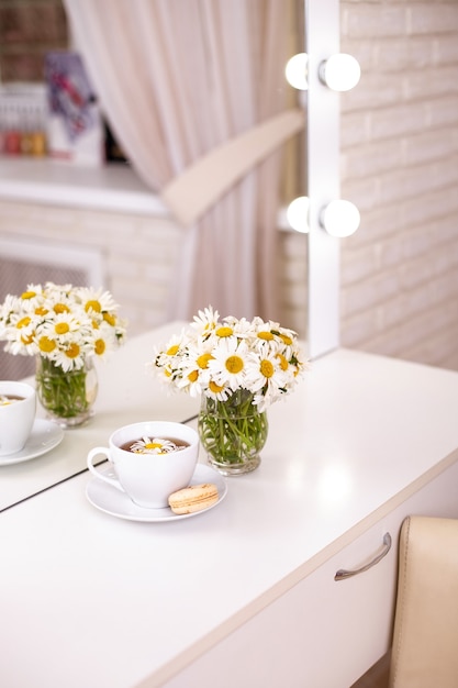 Les clients placent dans un salon de coiffure et de beauté avec une tasse de thé macaron et camomille dans un vase