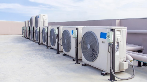 Climatisation (HVAC) sur le toit d'un bâtiment industriel avec ciel bleu et nuages.