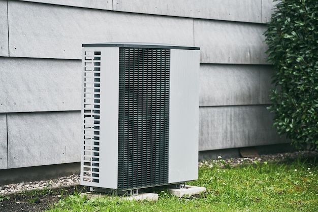 Un climatiseur à l'extérieur d'une maison dans l'herbe.