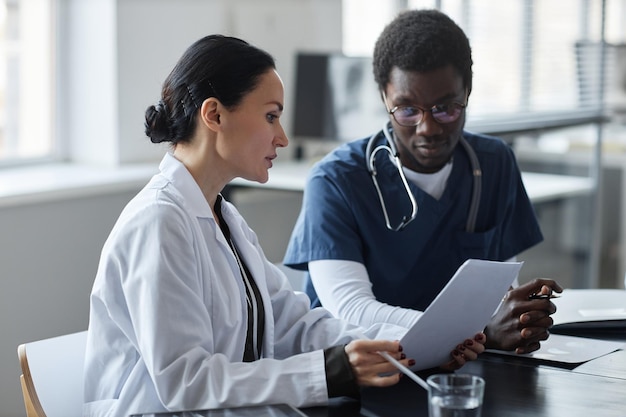 Une clinicienne confiante montre un document médical à un jeune assistant.