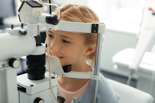 Clinique des yeux. Belle fille blonde aux yeux noirs portant un pull bleu venant à la clinique de soins privés