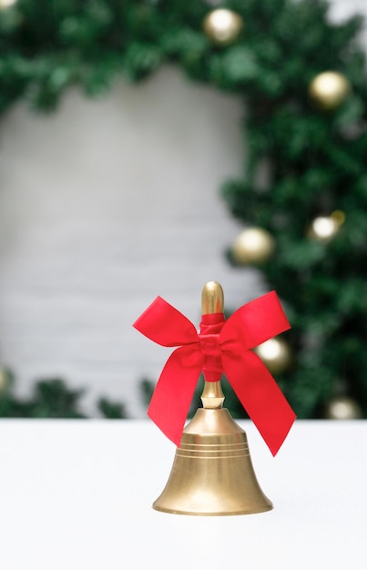 Cloche d'or avec le ruban rouge sur le fond blanc et la veille de l'arbre de Noël Nouvel An