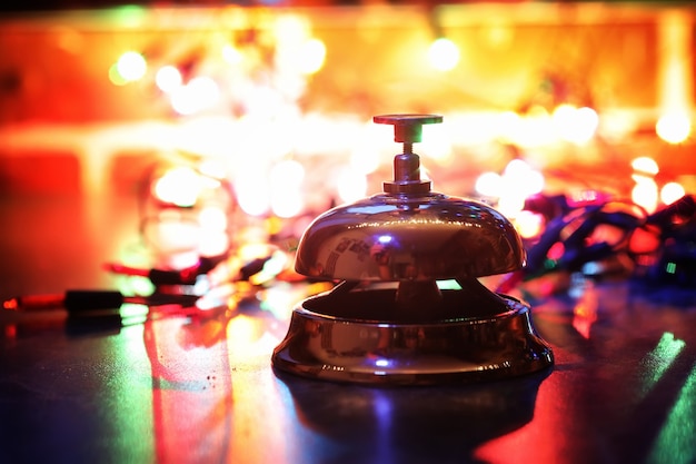 Cloche de réception sur la table et guirlande brillante de couleur sur fond