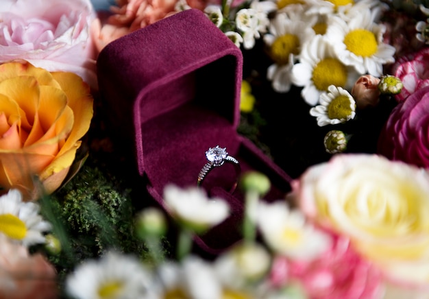 Cloeseup de bague de mariage dans une boîte rouge avec décoration arrangement de fleurs