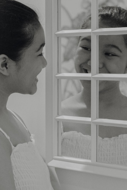 Photo close-up d'une adolescente d'asie du sud-est se regardant et souriant dans le miroir