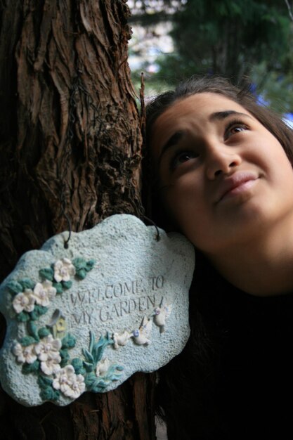 Photo close-up d'une adolescente réfléchie par le tronc d'un arbre
