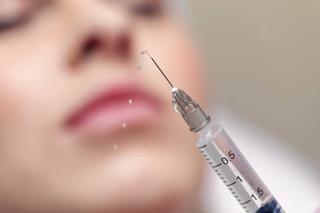 Close up aiguille d'une injection dans un salon de beauté. Liquide éclaboussant d'une seringue.