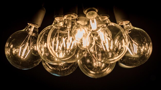 Photo close-up d'ampoules éclairées suspendues sur un fond noir