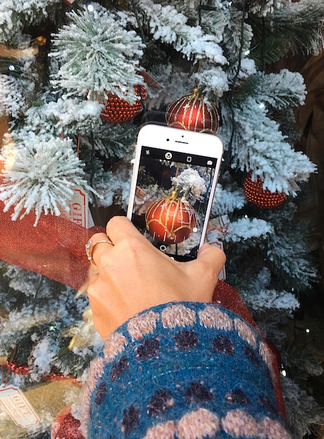 Close-up d'un arbre de Noël photographié à la main sur un smartphone pendant l'hiver