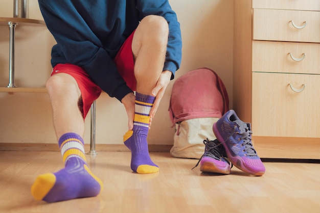 Close up athlète dans le vestiaire mettre des chaussettes et porter des vêtements de sport