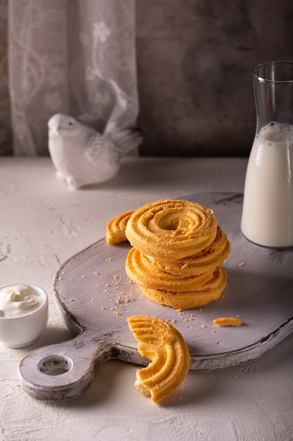 Close up de biscuits à la vanille et tasse de lait sur une planche de bois blanche