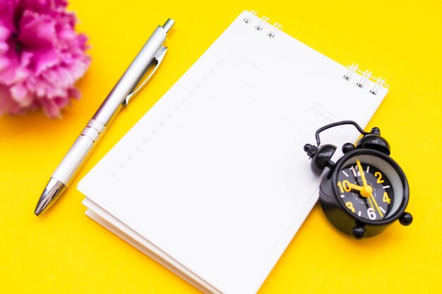 Photo close-up d'un bloc-notes avec une horloge sur un fond jaune