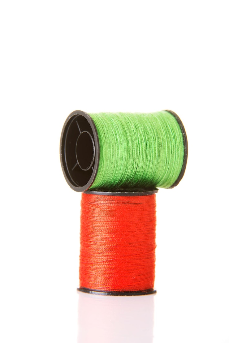 Photo close-up de bobines de fil rouge et vert sur fond blanc