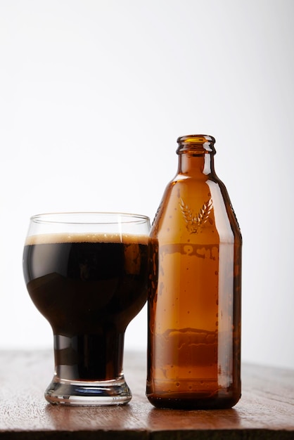 Photo close-up d'une boisson dans un verre par bouteille sur une table sur un fond blanc