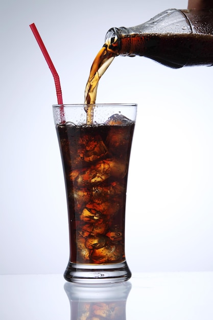 Photo close-up d'une boisson versée dans un verre à boire sur un fond blanc