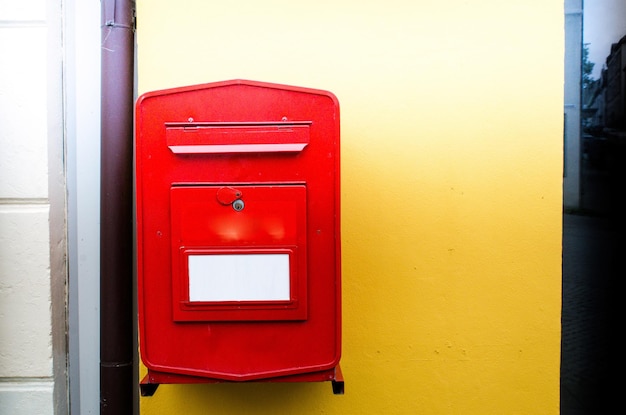 Photo close-up d'une boîte aux lettres rouge sur le mur jaune