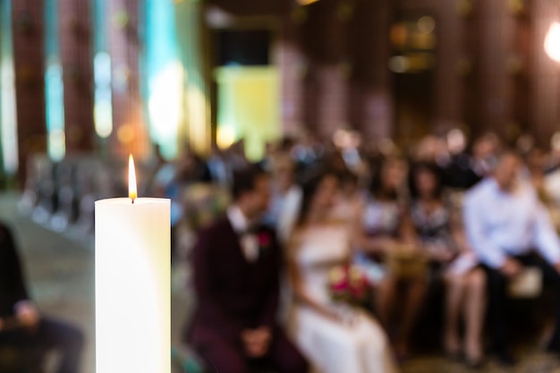 Photo close-up d'une bougie allumée avec des gens à l'église