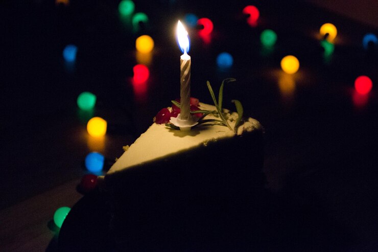 Photo close-up d'une bougie éclairée sur un morceau de gâteau