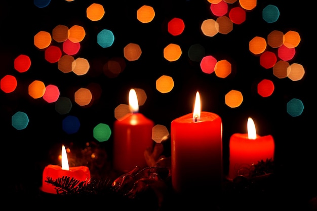 Photo close-up de bougies allumées contre les lumières de noël la nuit