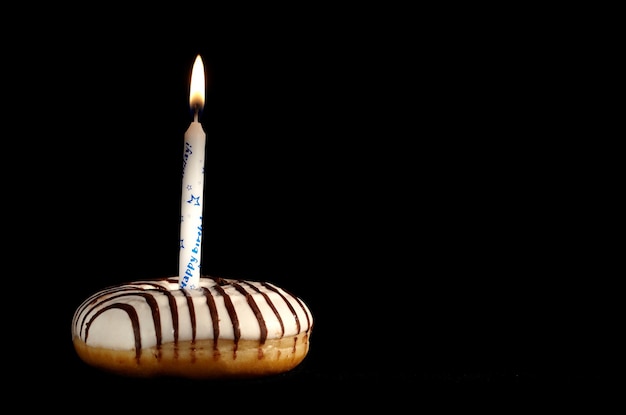 Photo close-up de bougies d'anniversaire sur un donut sur un fond noir