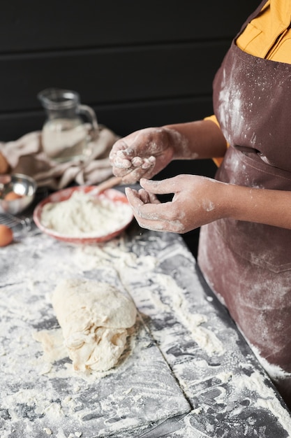 Close-up de boulanger avec de la farine sur ses mains pétrir une pâte dans la cuisine