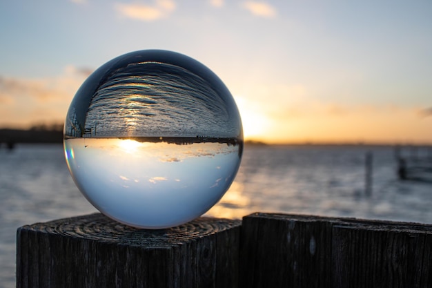 Close-up d'une boule de cristal sur un poteau de bois au coucher du soleil