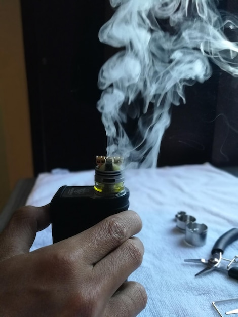 Close-up d'une bouteille à la main avec de la fumée émise sur la table