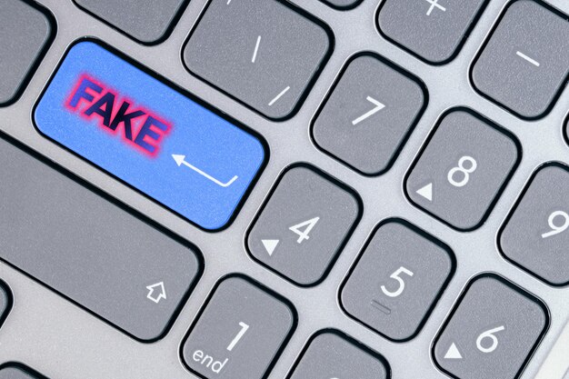Close-up d'un bouton bleu avec un faux texte sur un clavier conceptuel concept de tromperie et