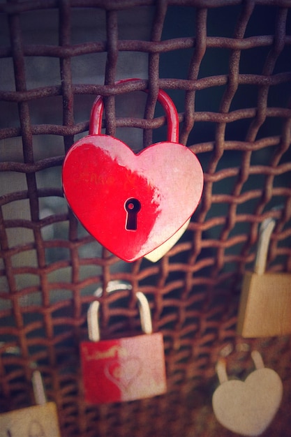 Photo close-up d'un cadenas en forme de cœur rouge dans une clôture