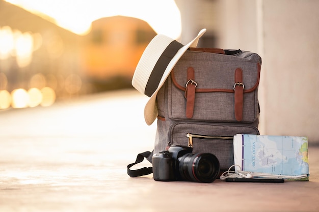 Close-up de la caméra par chapeau de soleil sur le sac et les écouteurs dans l'oreille avec la carte du monde sur la terre