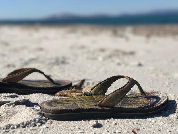 Photo close-up de chaussures sur le sable à la plage contre le ciel