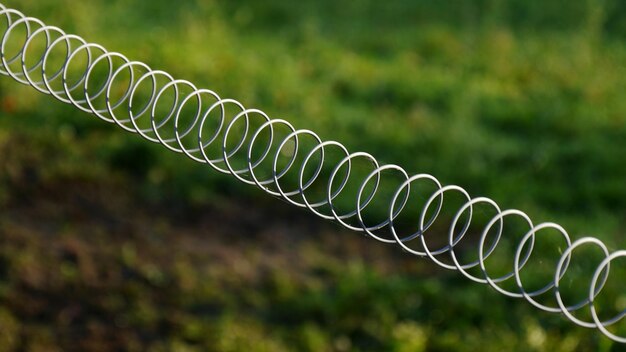 Close-up d'une clôture métallique en spirale sur un pâturage de bétail