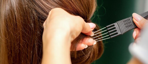 Close Up coiffeur styliste fait coiffure pour une jeune femme dans un salon de beauté.