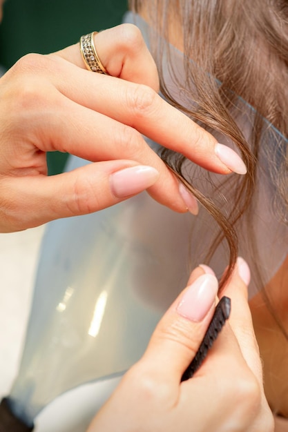 Close Up coiffeur styliste fait coiffure pour une jeune femme dans un salon de beauté.