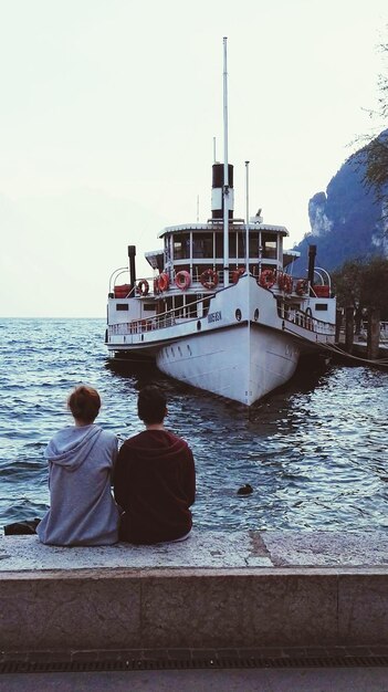 Photo close-up d'un couple assis avec un bateau en arrière-plan