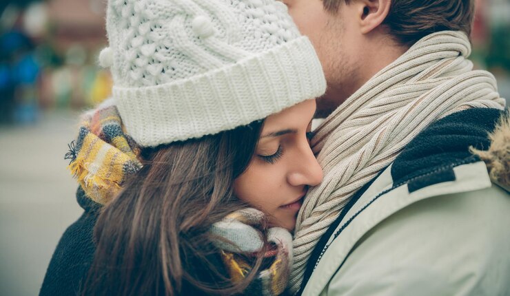 Photo close-up d'un couple s'embrassant en portant des vêtements chauds en ville