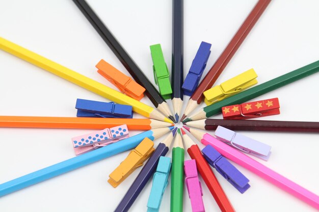Close-up de crayons de couleur avec des pinces à linge colorées sur fond blanc