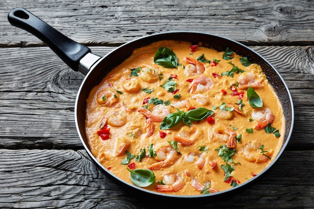 Close-up de crevettes crémeuses en sauce noix de coco avec un mélange de légumes et d'herbes dans une poêle, camarao no leite de coco