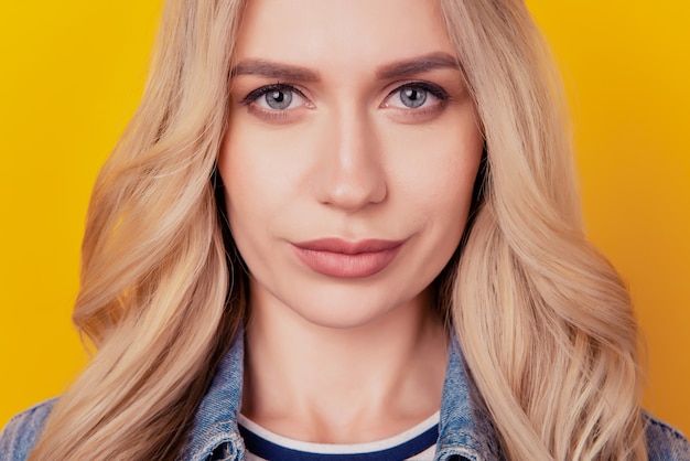 Close-up cropped portrait of blonde lady look tentant caméra sourire sur fond jaune